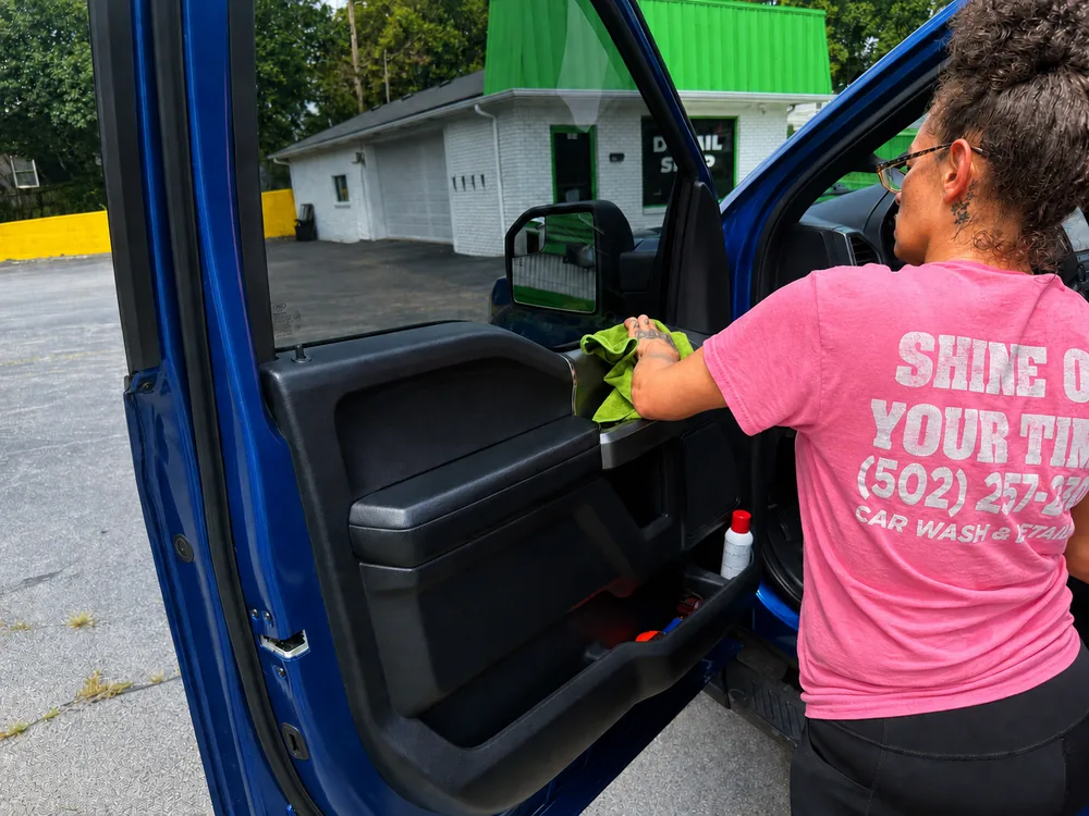 A Shine On Your Time detailer wiping down a truck door panel by hand at the detail shop