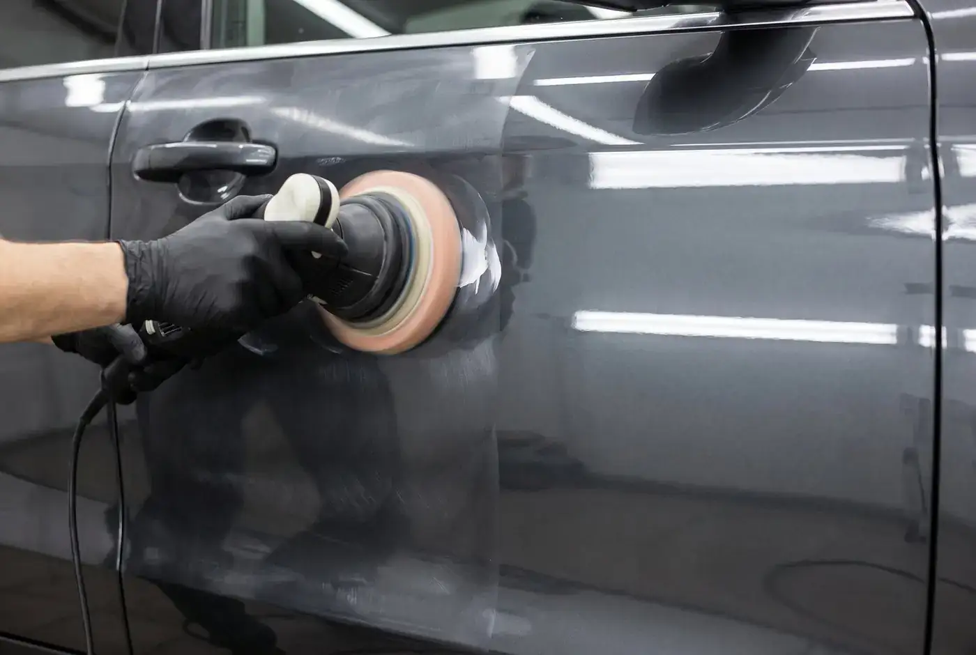 A Shine On Your Time detailer machine polishing a dark gray car door during a Platinum auto detailing service in Kentucky